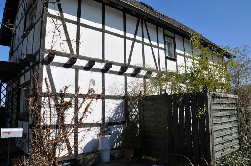 Ein weiß-schwarzes Haus mit einem Holzzaun davor