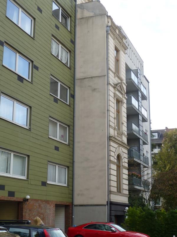 Ein rotes Auto steht vor einem hohen Gebäude