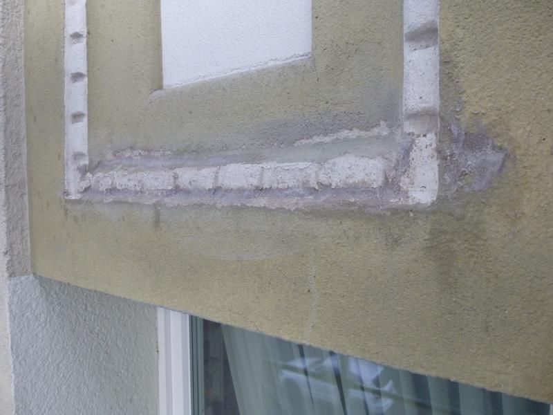 Eine Nahaufnahme eines Fensters an einem Gebäude mit einem zerbrochenen Rahmen.