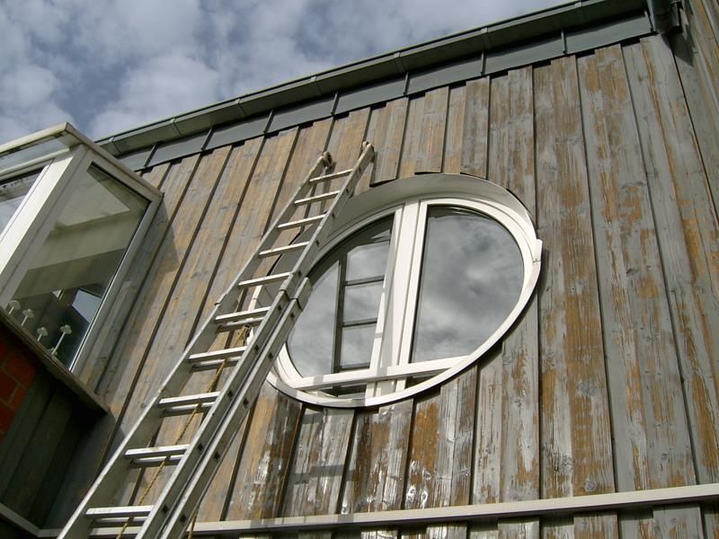 Ein Holzgebäude mit einem runden Fenster und einer Leiter
