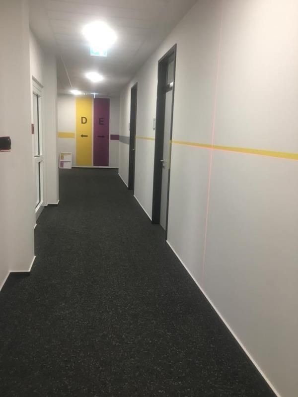 Ein langer Flur mit violetten und gelben Türen