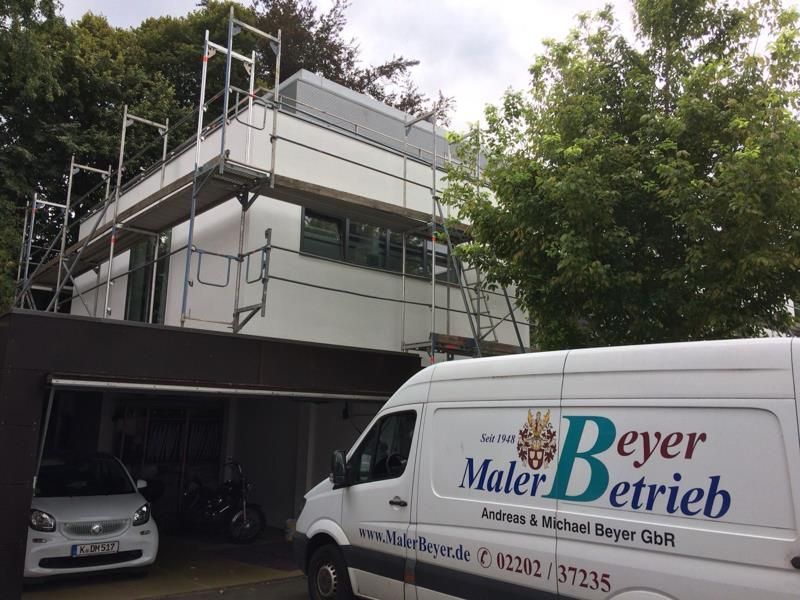 Ein weißer Lieferwagen mit der Aufschrift „Beyer Maler Betrieb“ steht vor einem Gebäude