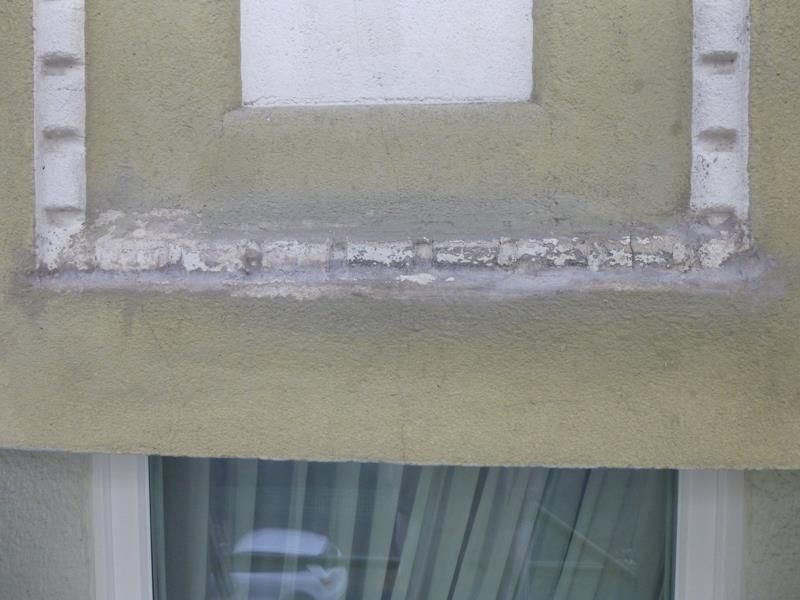 Ein Fenster an der Seite eines Gebäudes mit abblätternder Farbe