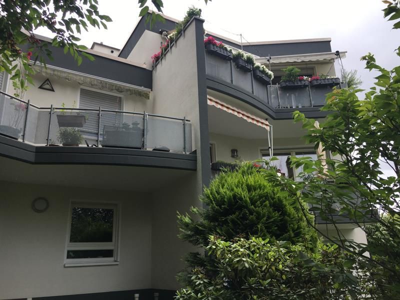 Ein großes weißes Gebäude mit einem Balkon und Bäumen davor