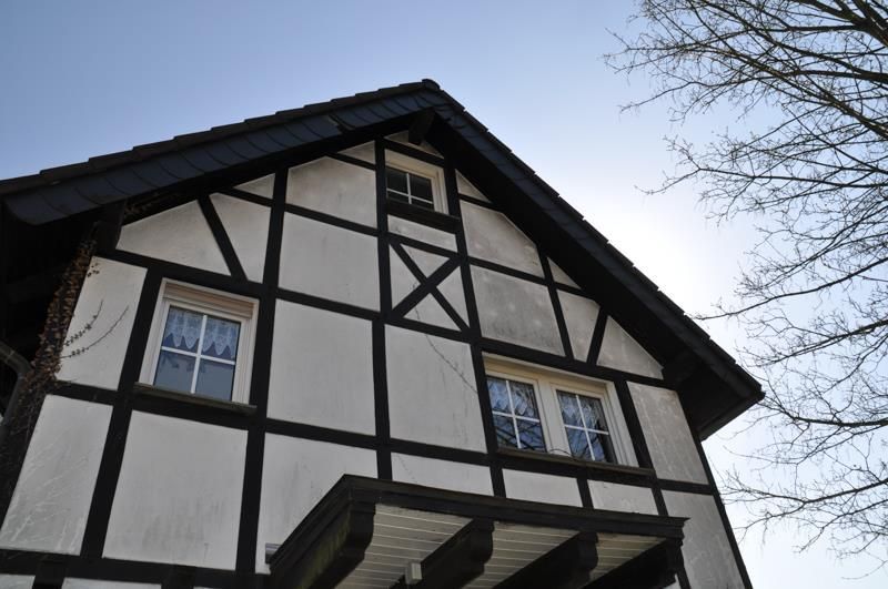 Ein weiß-schwarzes Haus mit einem Dach, auf dem ein Kreuz steht