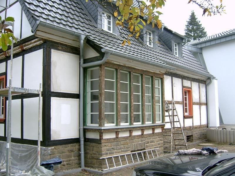 Ein schwarzes Auto steht vor einem im Bau befindlichen Haus