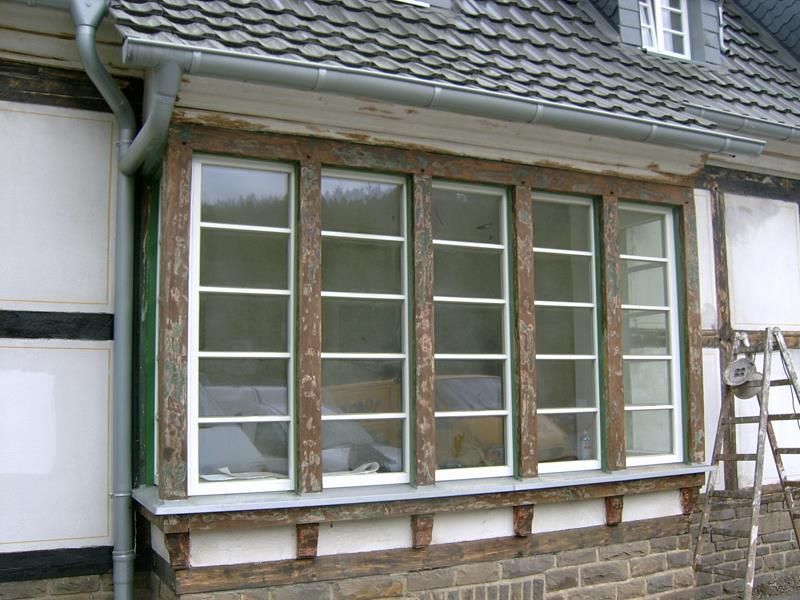 Eine Leiter lehnt an einem Gebäude mit einem großen Fenster