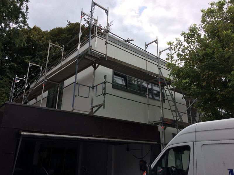 Ein weißer Lieferwagen parkt vor einem im Bau befindlichen Gebäude.