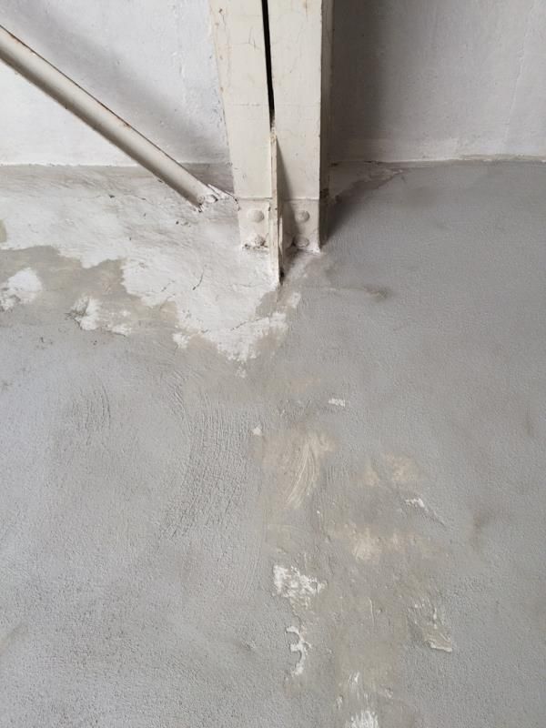 Eine Nahaufnahme eines Betonbodens mit einer Säule im Hintergrund.