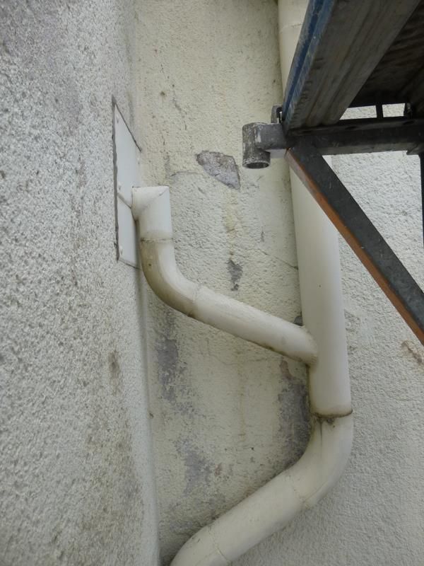 Ein weißes Rohr ist an einer weißen Wand befestigt