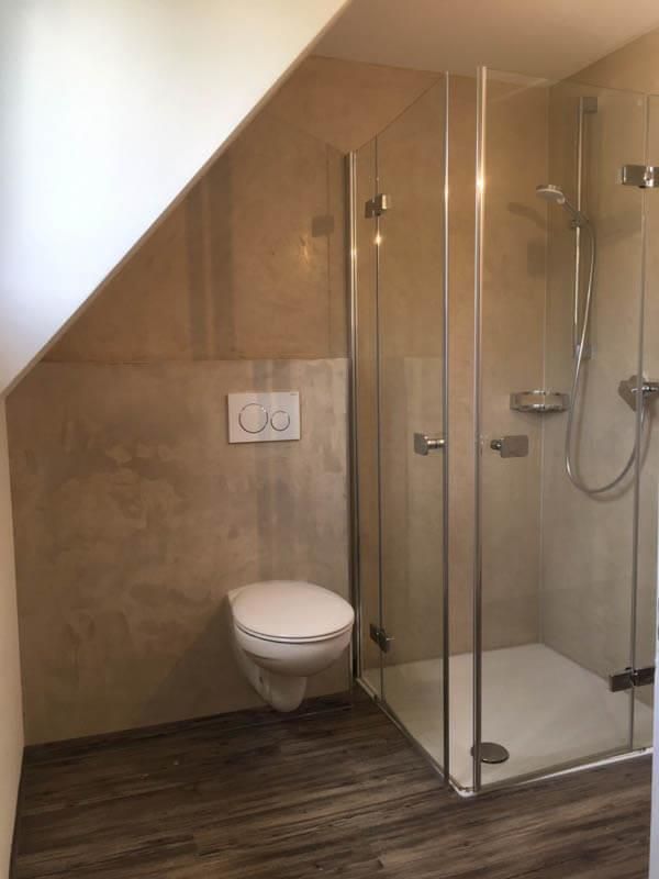 Ein Badezimmer mit Toilette und ebenerdiger Dusche.