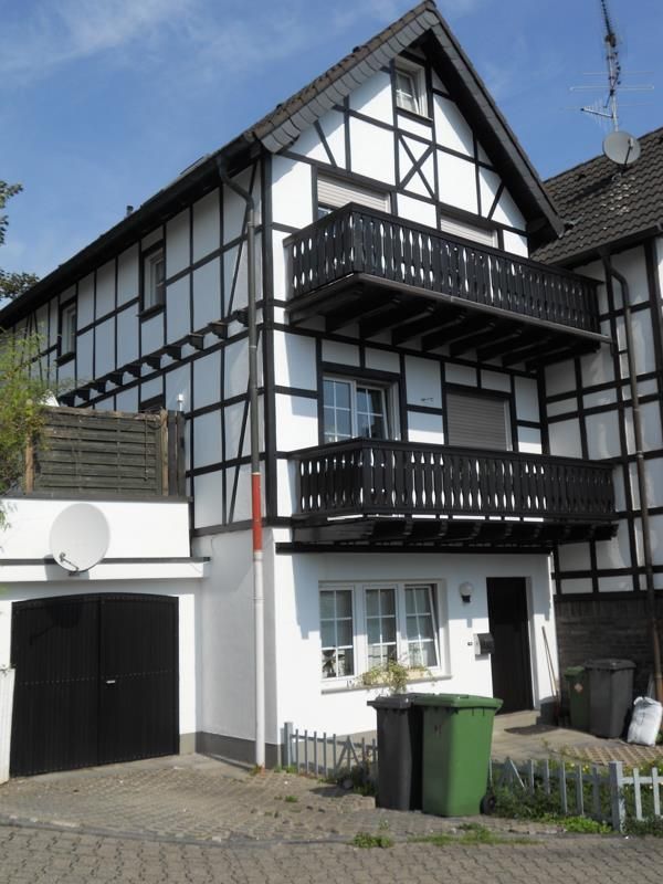 Ein schwarz-weißes Haus mit einem Balkon im zweiten Stock