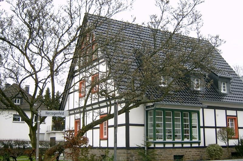 Ein weißes Haus mit schwarzem Dach und einem Baum davor