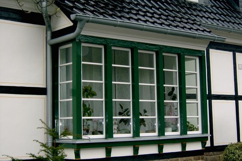 Ein Haus mit einem grün-weißen Fenster mit Pflanzen darin