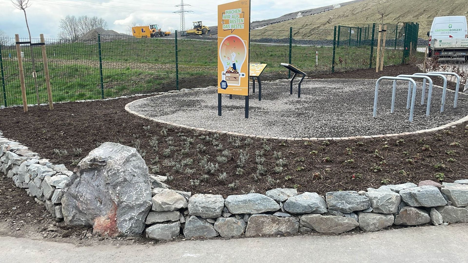 Eine Steinmauer umgibt einen kreisförmigen Bereich mit einem Schild in der Mitte.