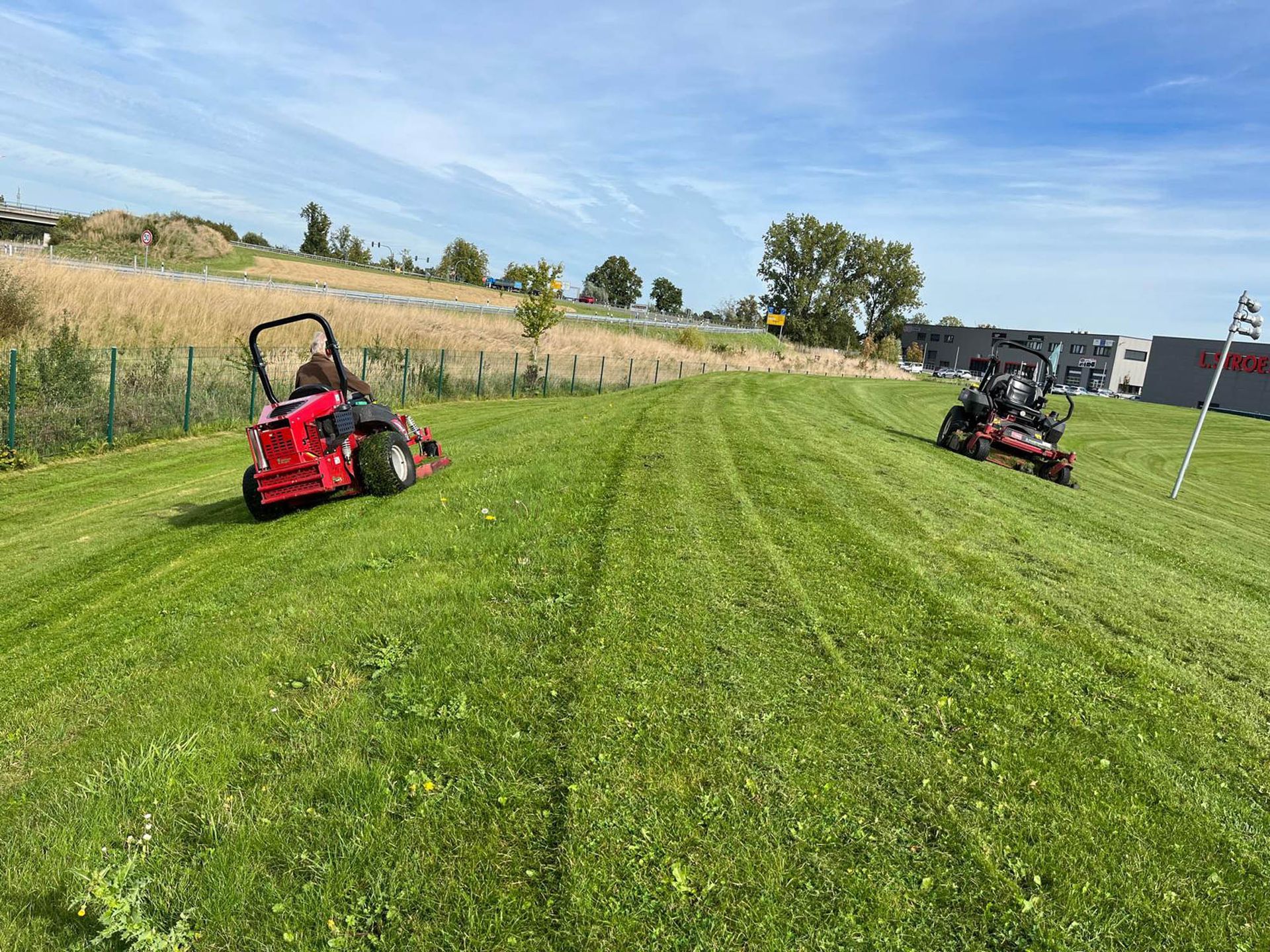 Zwei Rasenmäher mähen einen saftig grünen Rasen.