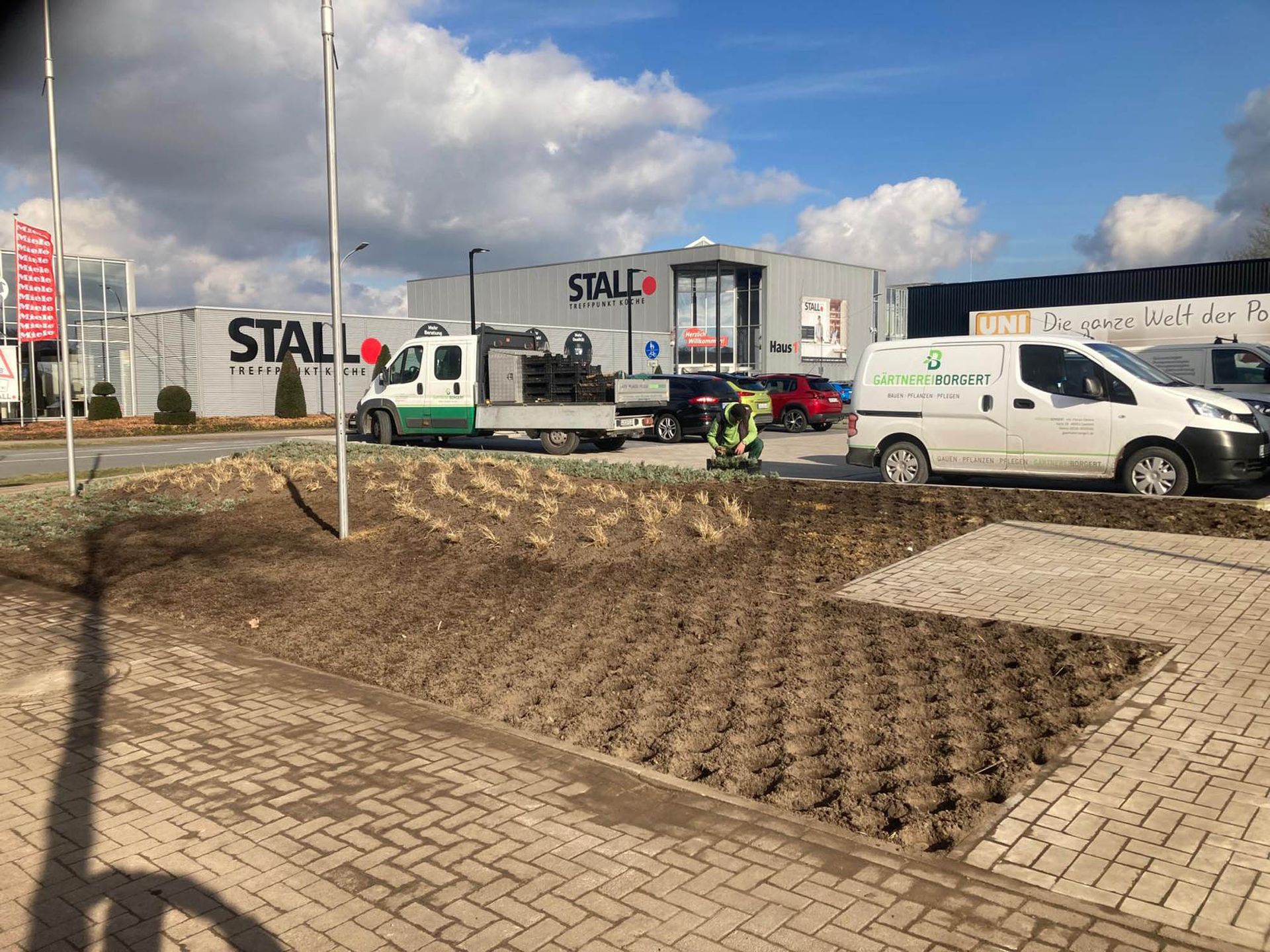 Ein weißer Lieferwagen steht vor einem Stallgebäude.