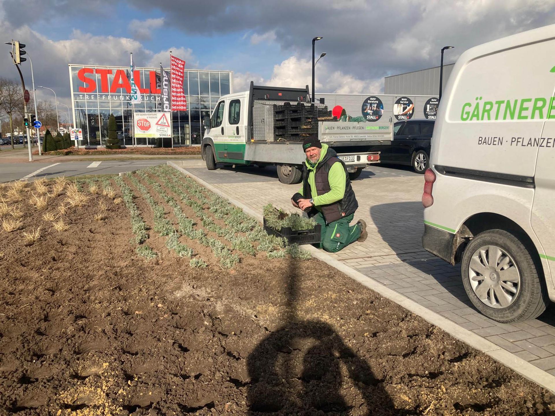 Ein Mann kniet auf einem Parkplatz neben einem Lieferwagen.