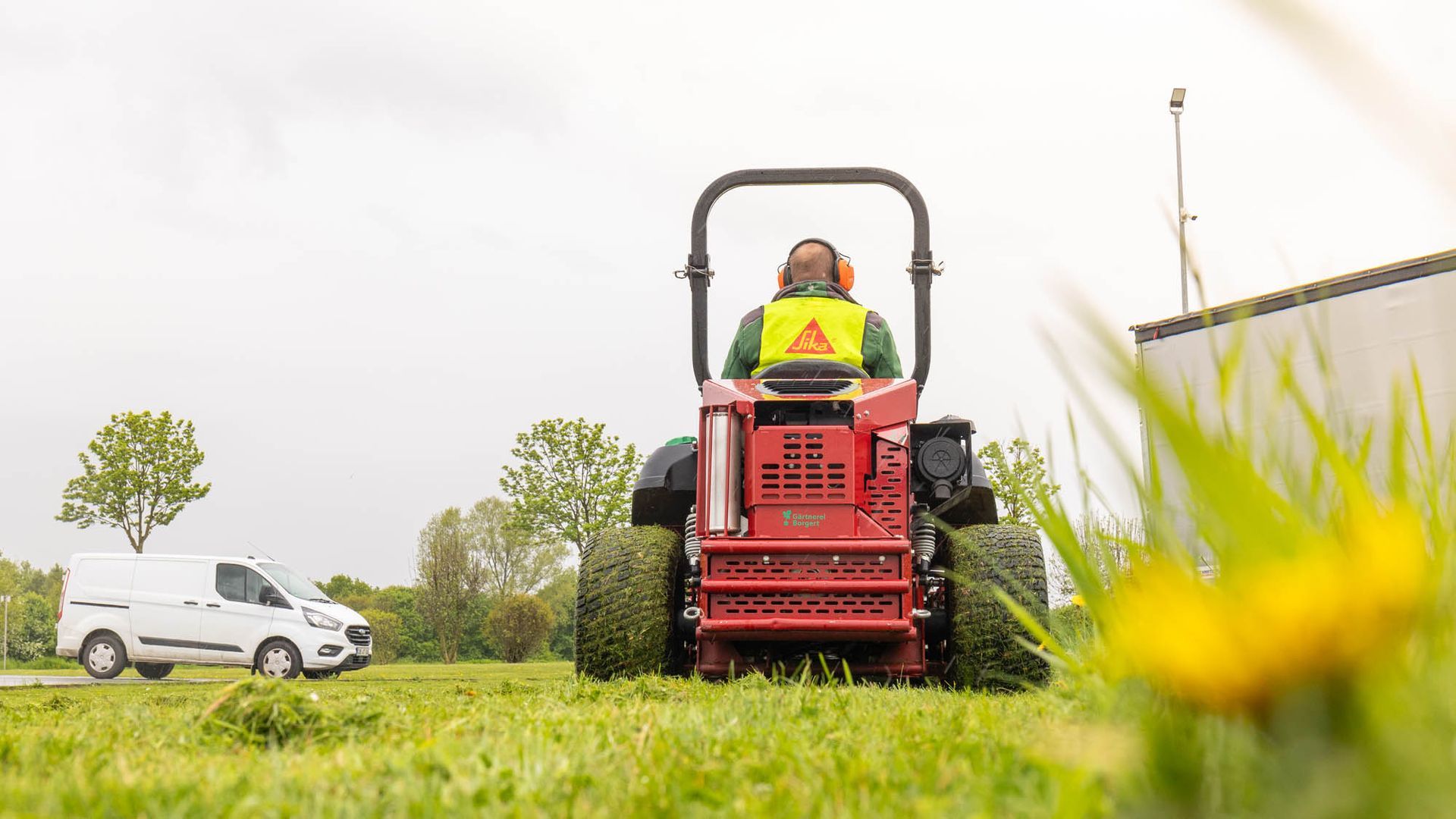 Ein Mann fährt mit einem Rasenmäher über eine Wiese.