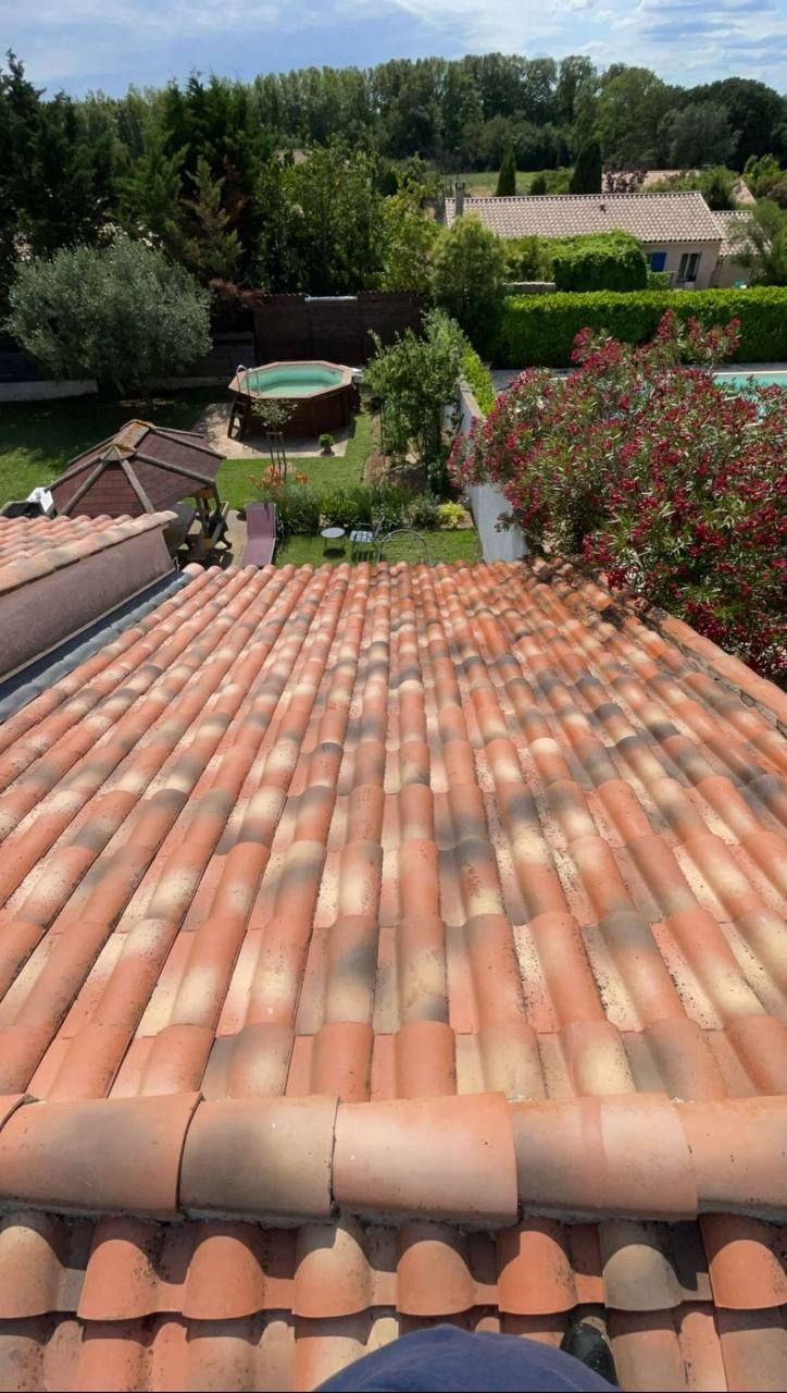 Toit de tuiles rouges donnant sur un jardin avec piscine et verdure.