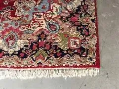 Eine Nahaufnahme eines Teppichs mit Fransen auf einem Betonboden.