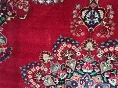 Eine Nahaufnahme eines roten Teppichs mit einem Blumenmuster.