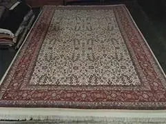 Ein großer Teppich liegt auf einem Holzboden in einem Wohnzimmer.