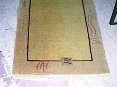 Auf einem Betonboden liegt neben einem Stuhl ein Teppich.