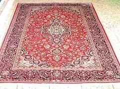 Auf einem gefliesten Boden liegt ein großer roter Teppich.