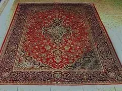 Auf einem Holzboden liegt ein großer roter Teppich.