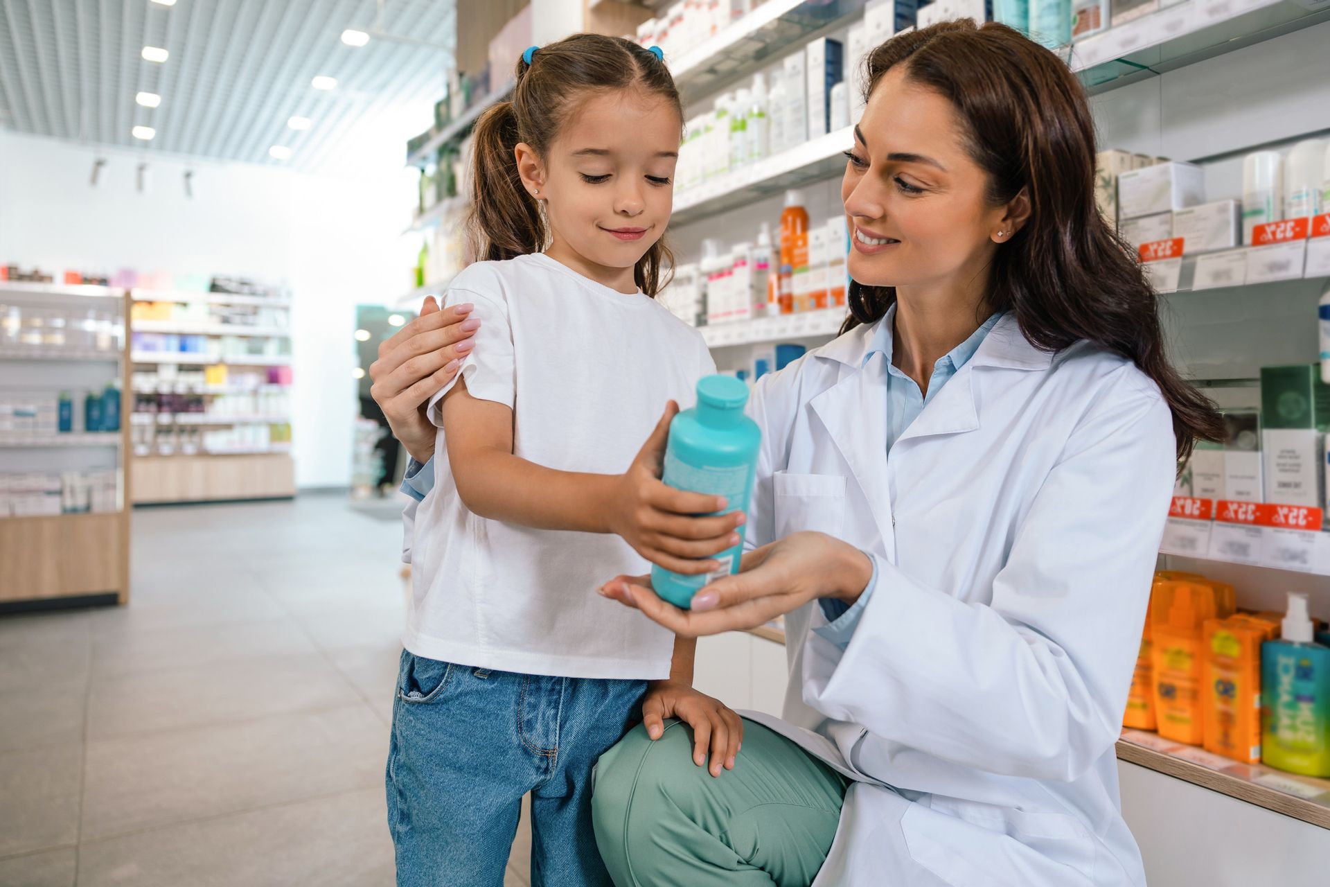 Farmacéutico mostrando a un niño una botella azul en una farmacia.