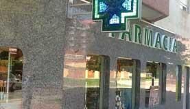 Una farmacia con un cartel al costado.