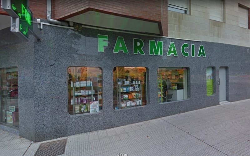 Una farmacia con un cartel verde en el costado del edificio.