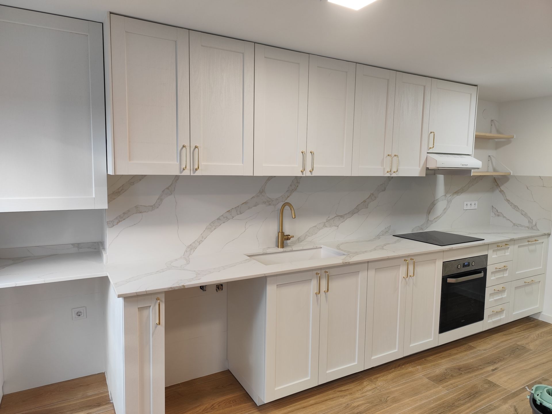 Una cocina con gabinetes blancos, una estufa y un fregadero.