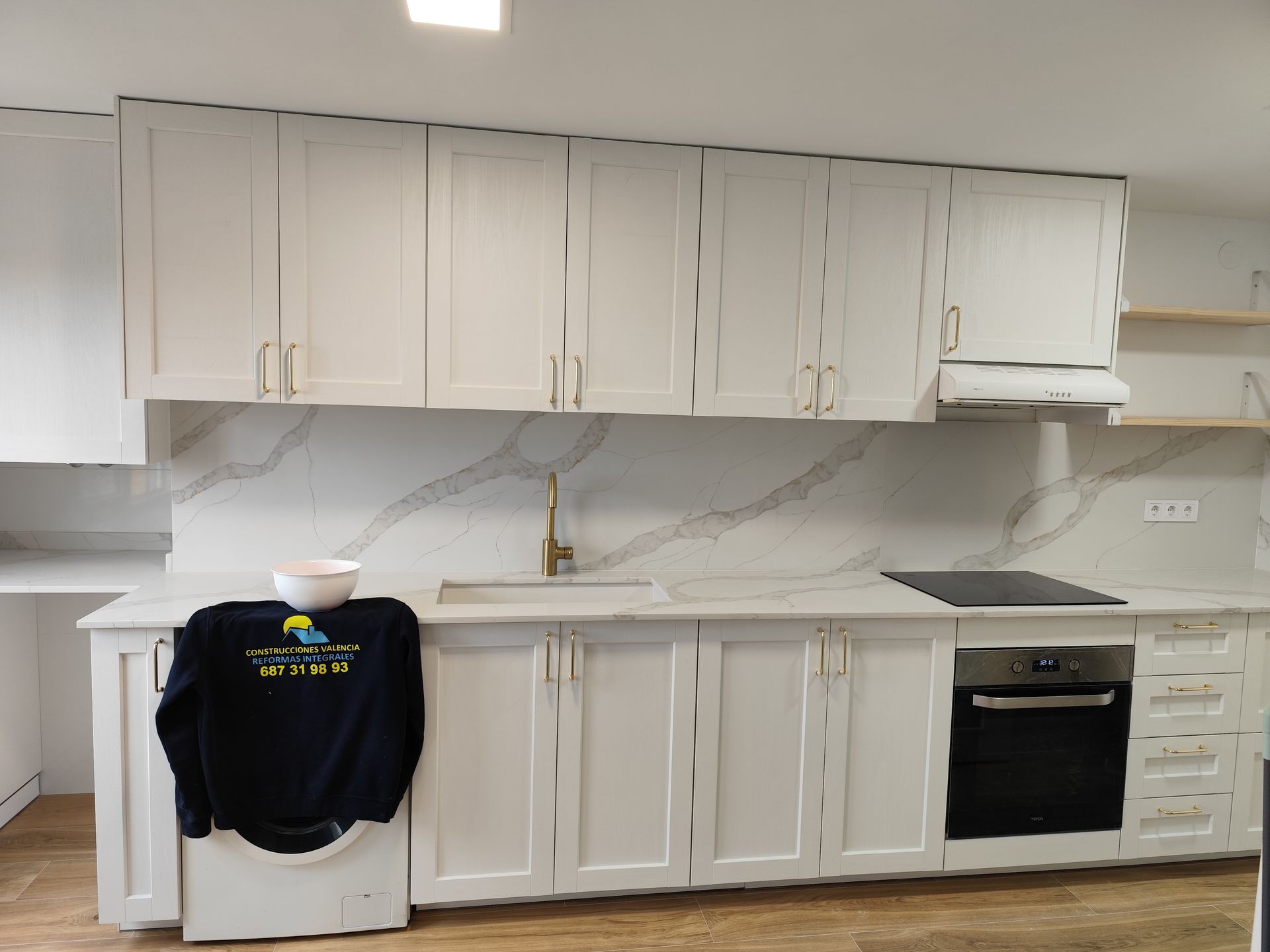 Una cocina con gabinetes blancos y una camisa negra en la encimera.