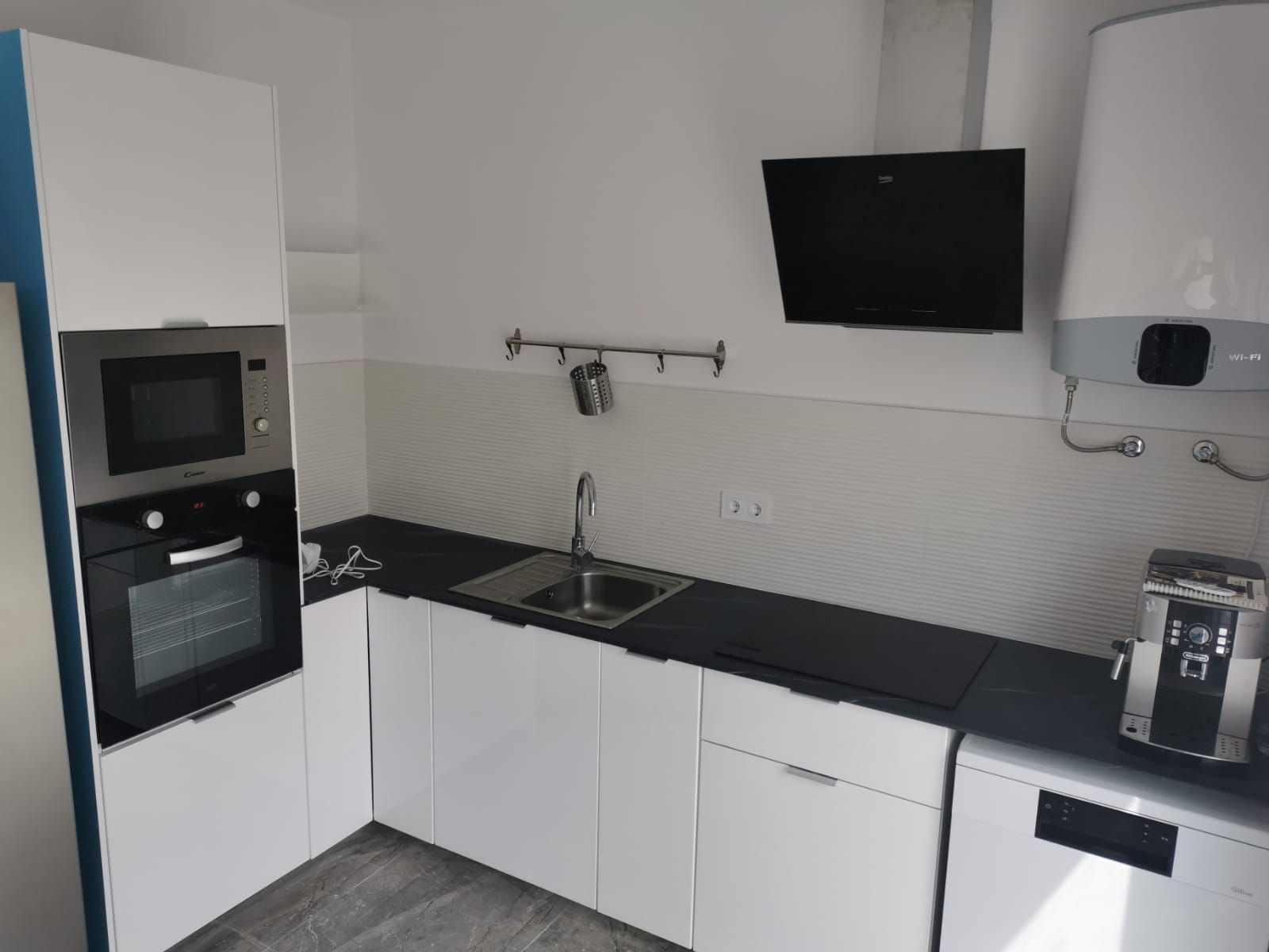 Una cocina con gabinetes blancos y encimeras negras.