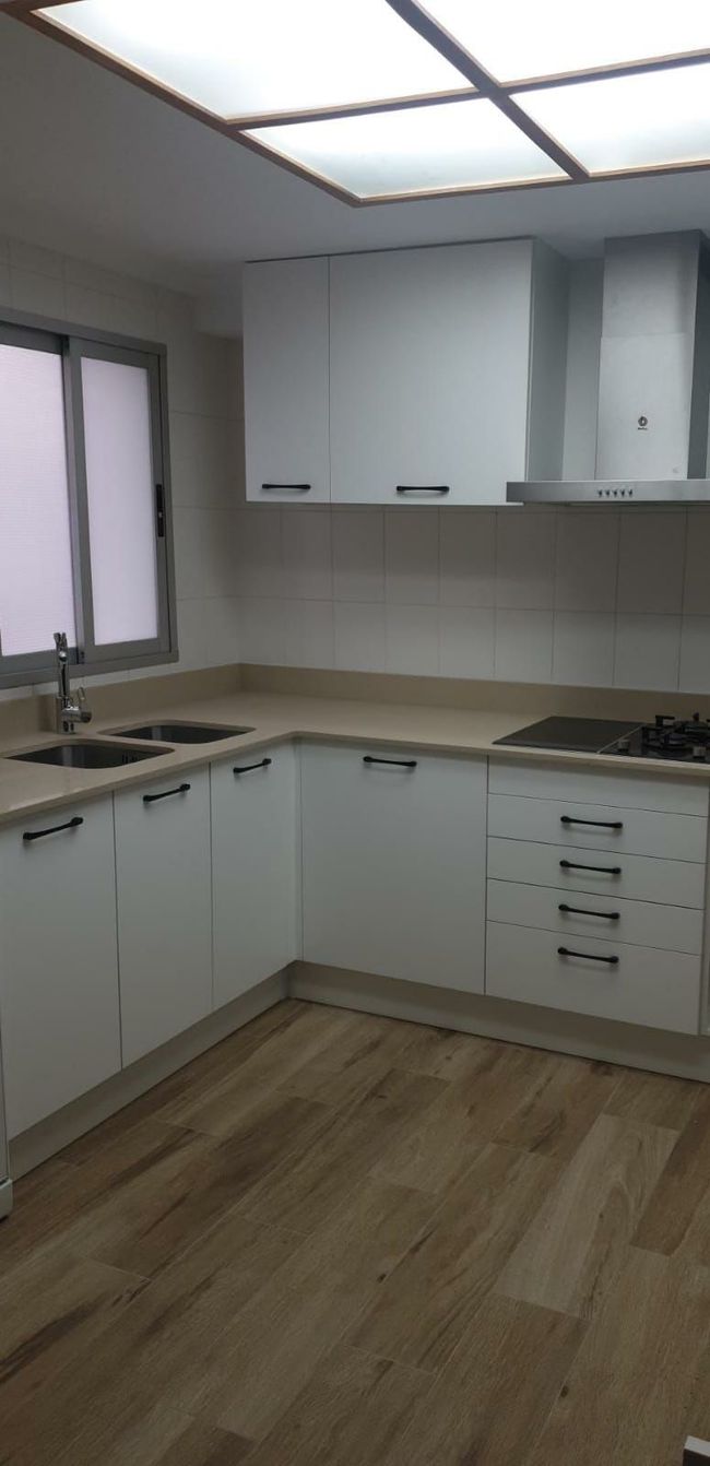 Una cocina con gabinetes blancos y pisos de madera.