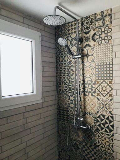 Una ducha con cabezal de ducha y ventana en un baño.