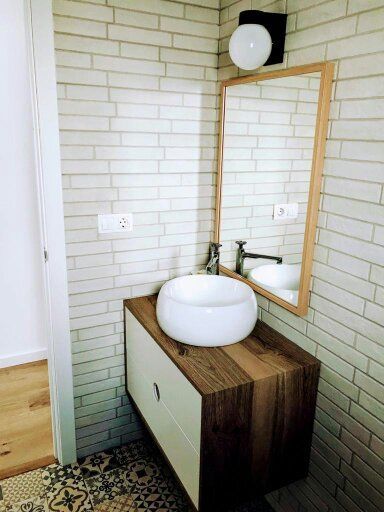 Un baño con lavabo, espejo y pared de ladrillo.