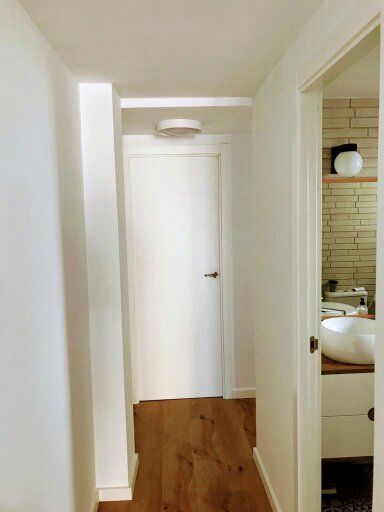 Un pasillo que conduce a un baño con lavabo y espejo.