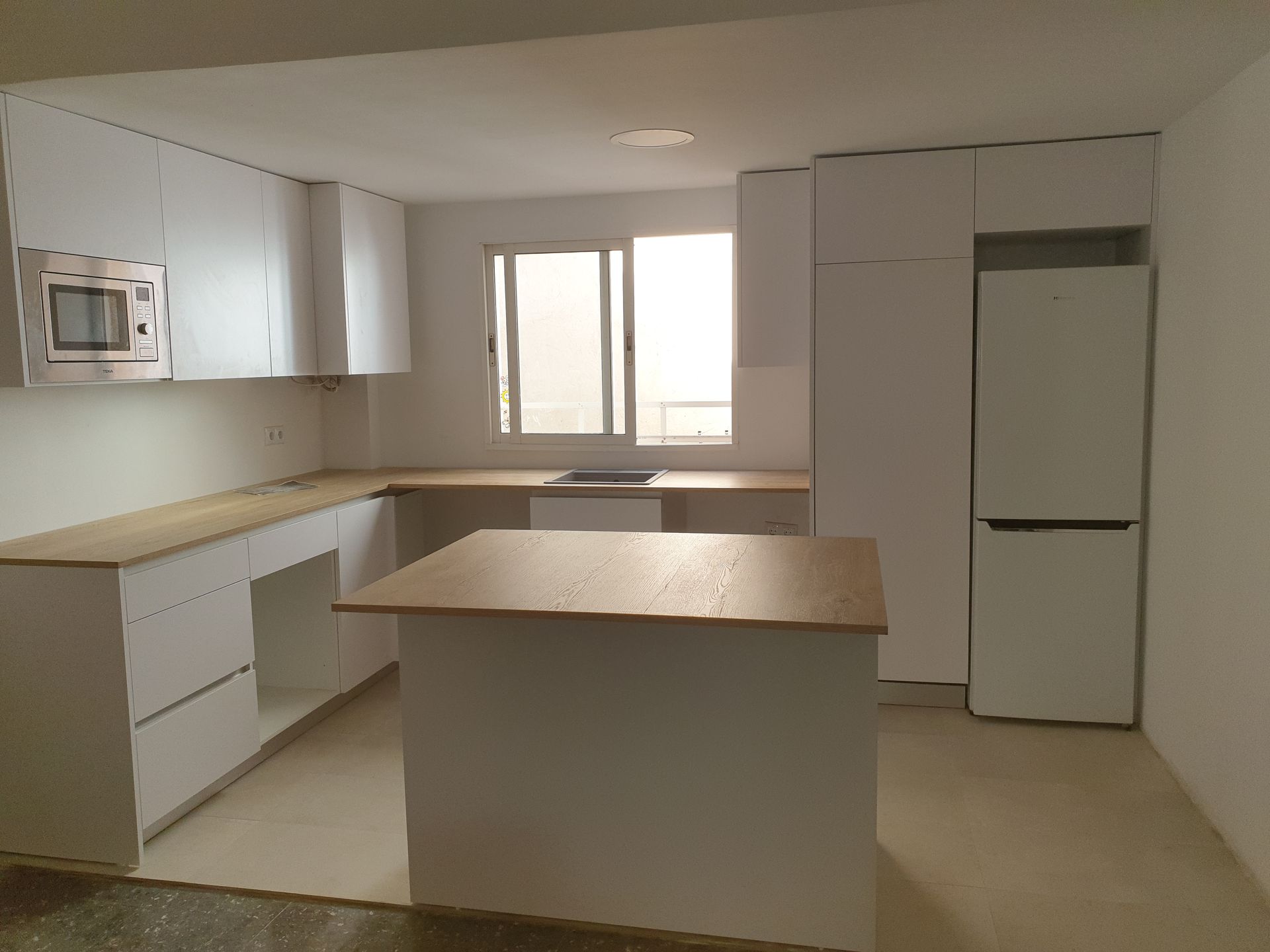 Una cocina con gabinetes blancos y encimeras de madera.