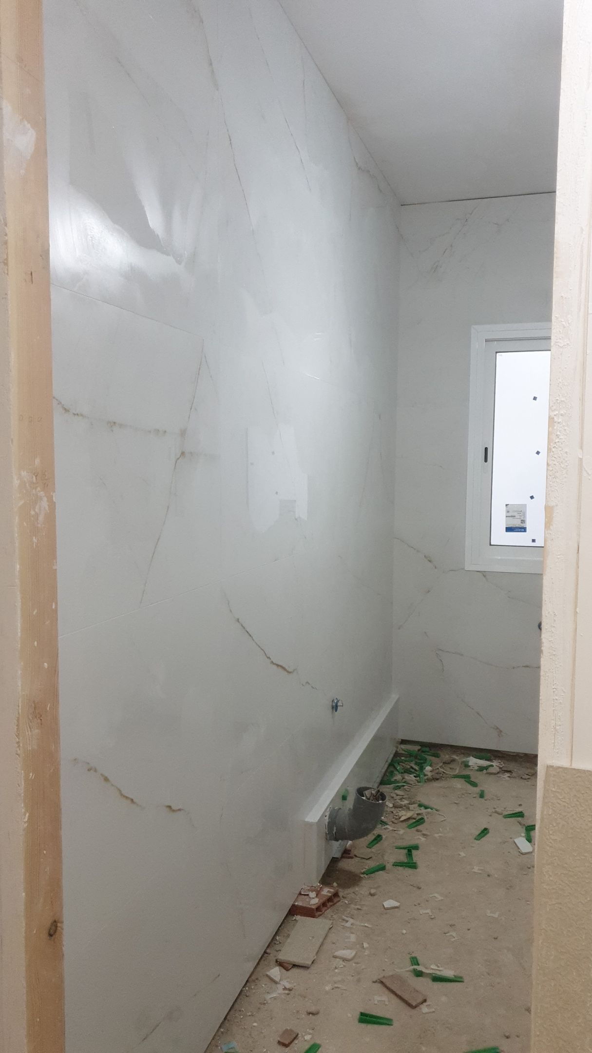 Un baño en construcción con una ventana y una pared blanca.