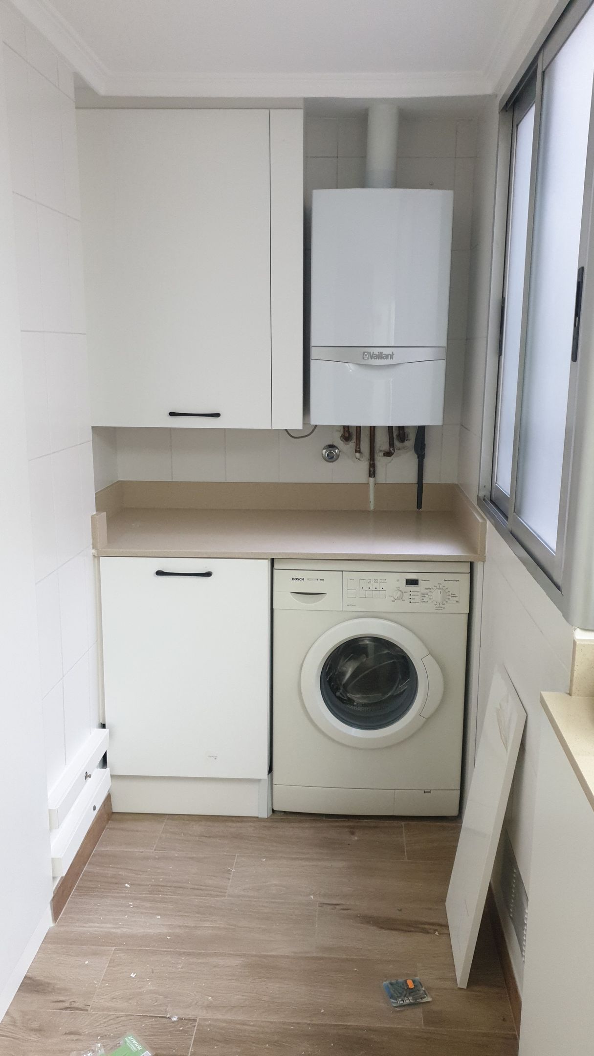 Un lavadero con lavadora y secadora y una ventana.