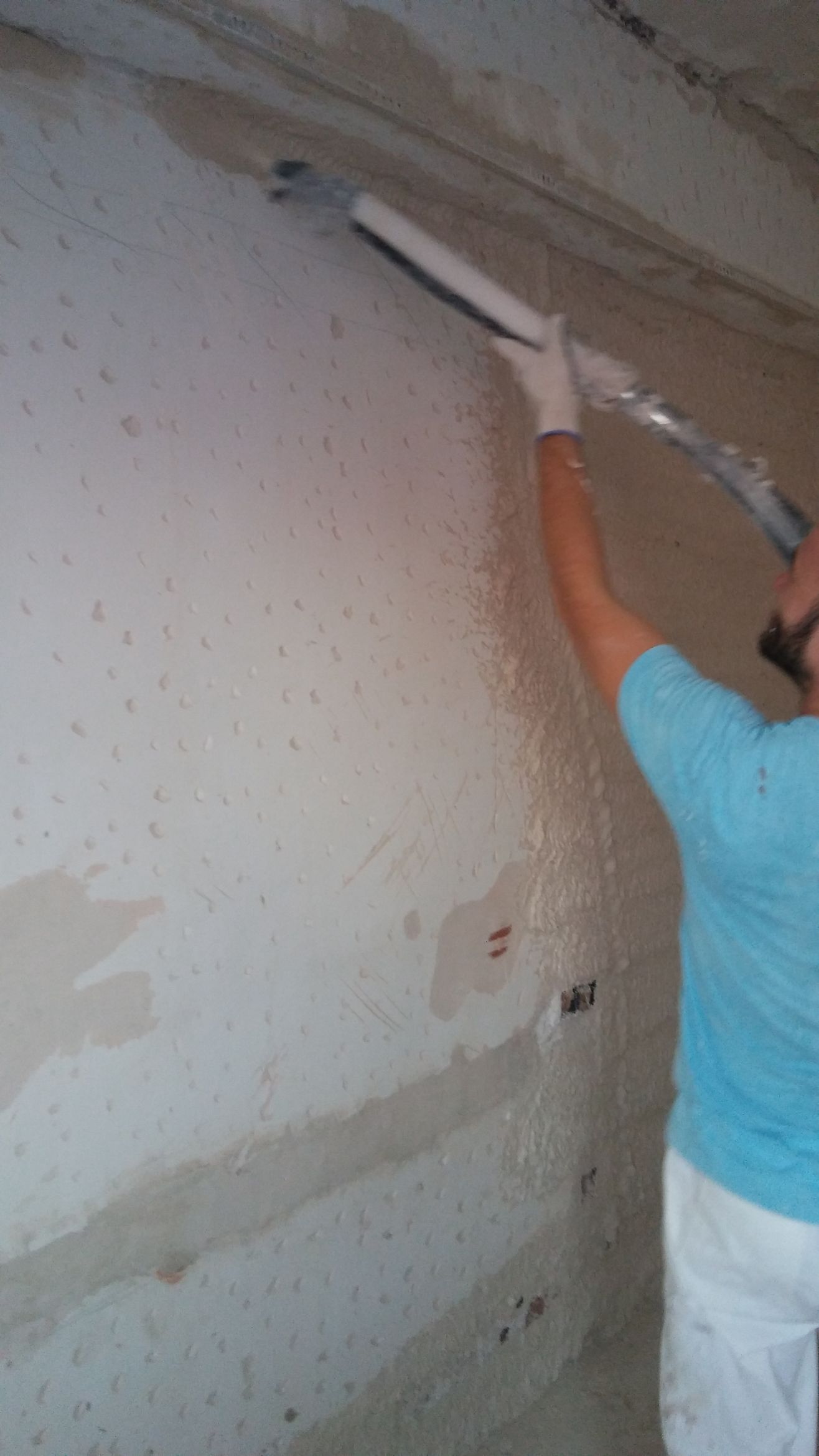 Un hombre está pintando una pared con un rodillo de pintura.