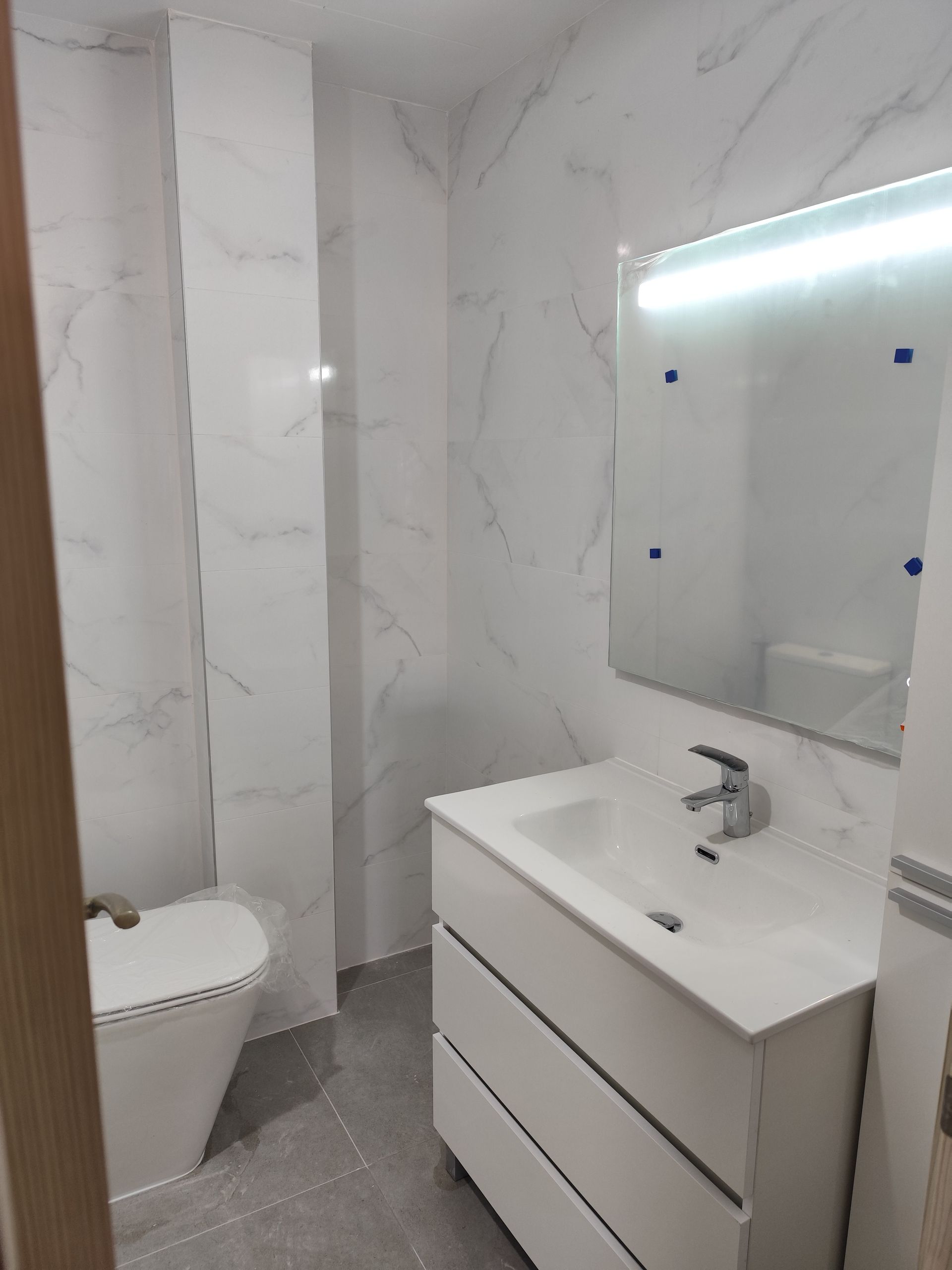 Un baño con inodoro, lavabo y espejo.