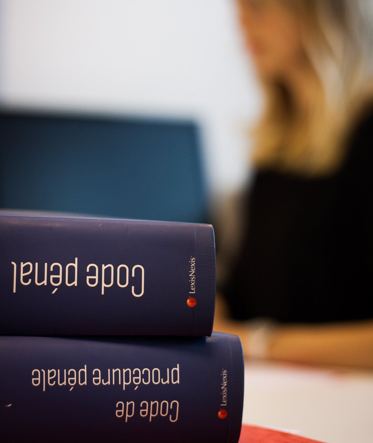 Des livres intitulés Code pénal et Code de procédure pénale empilés, Maître Jeannot floue en arrière-plan.