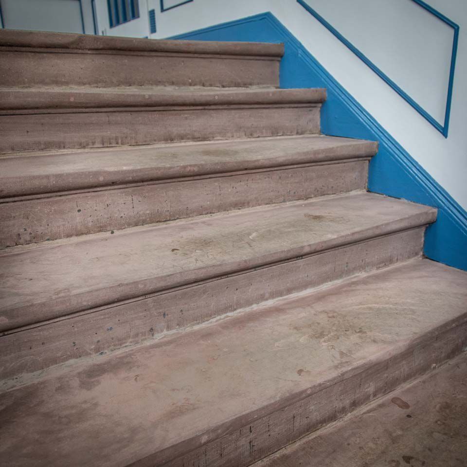 Steintreppe mit blauem Rand an einer weißen Wand.