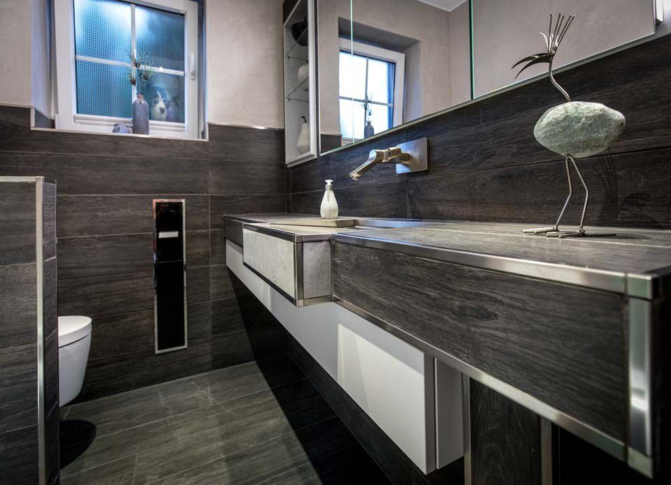 Modernes Badezimmer mit grauen Steinfliesen, schwebendem Waschtisch und dekorativer Vogelskulptur.