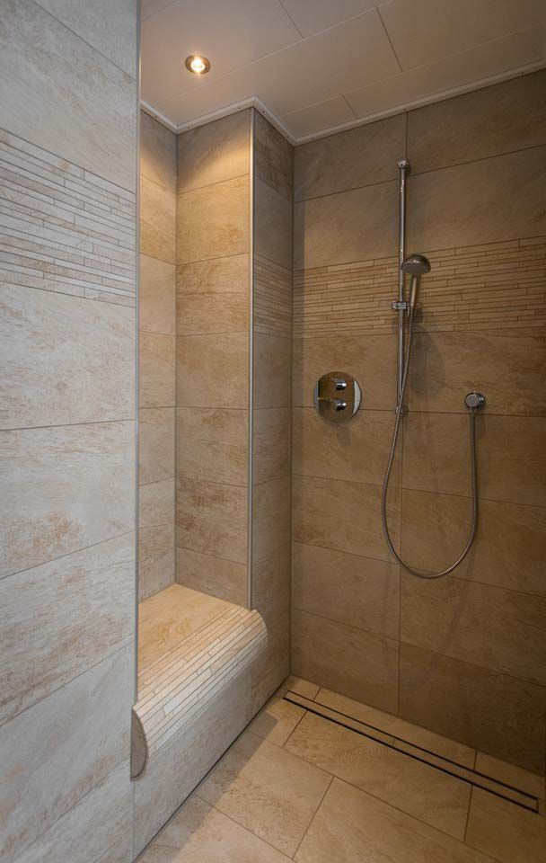Moderne Dusche mit beigefarbenen Fliesen, integriertem Sitz und Regenduschkopf.