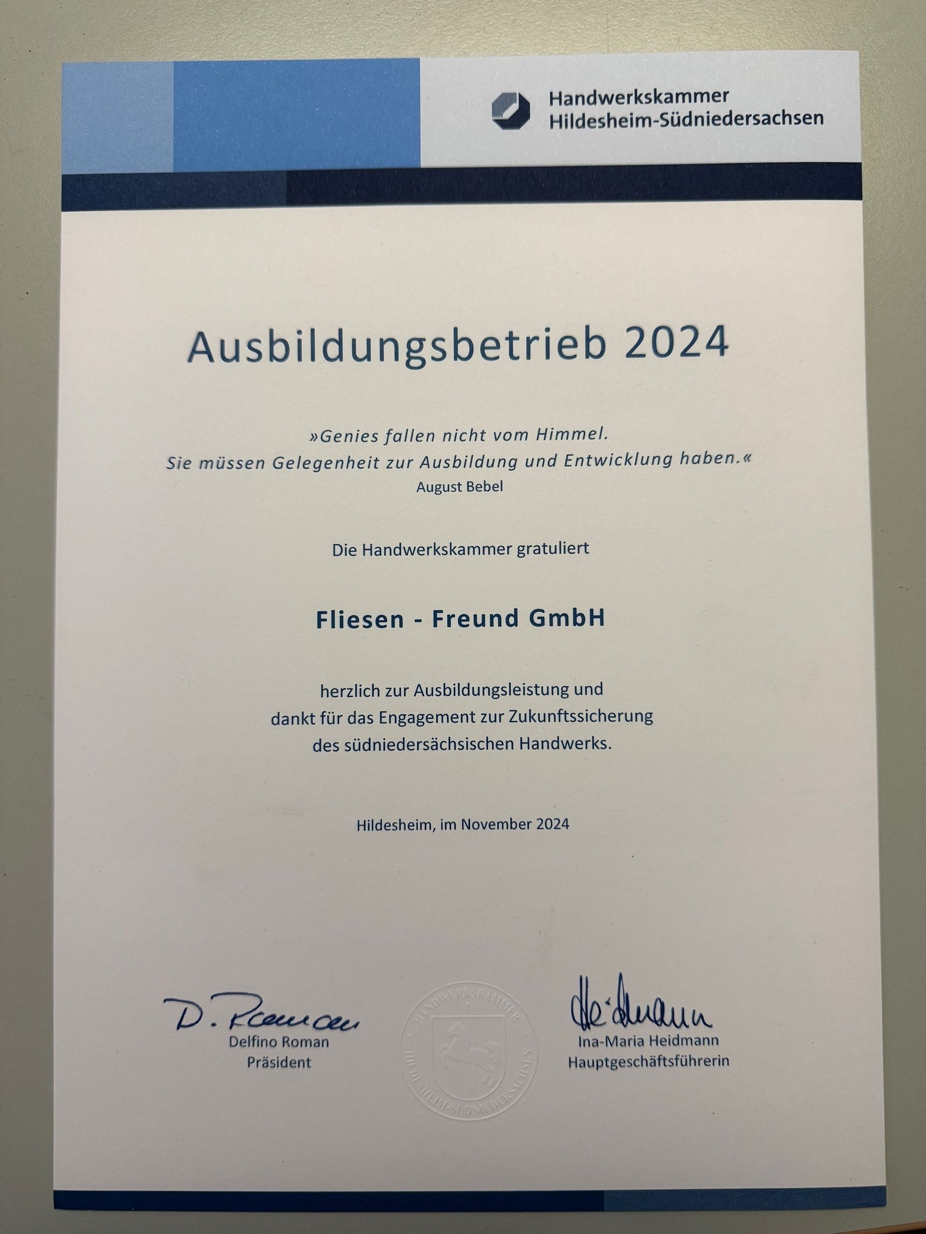 Weißes Dokument mit dem Titel „Ausbildungsbetrieb 2024“ und blauer Kopfzeile, von zwei Personen unterzeichnet.